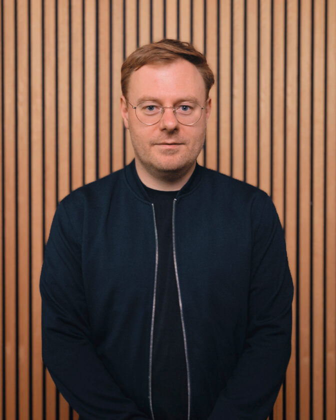 Portrait von Marcel Pietsch vor einer Holzlamellenwand