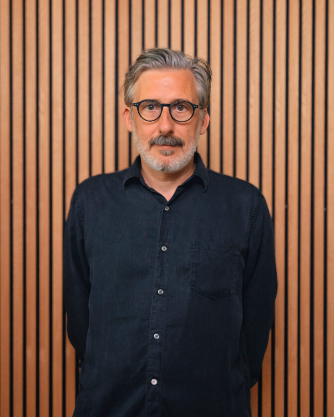 Portrait von Oliver Hunke vor einer Holzlamellenwand