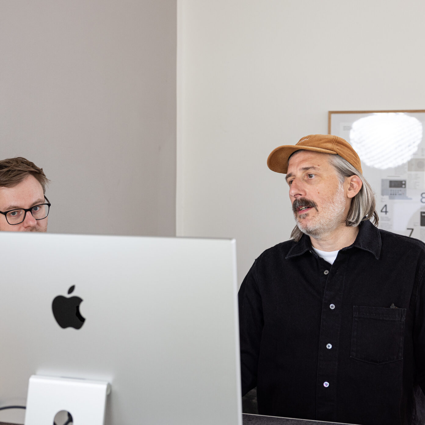 Digitalagentur Chef Olli spricht mit Webdesigner Marcel über die Gestaltung einer Website eines Kunden.