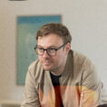 Webdesigner Marcel sieht zu einem Kollegen mit dem er sich über ein WordPress Projekt unterhält.