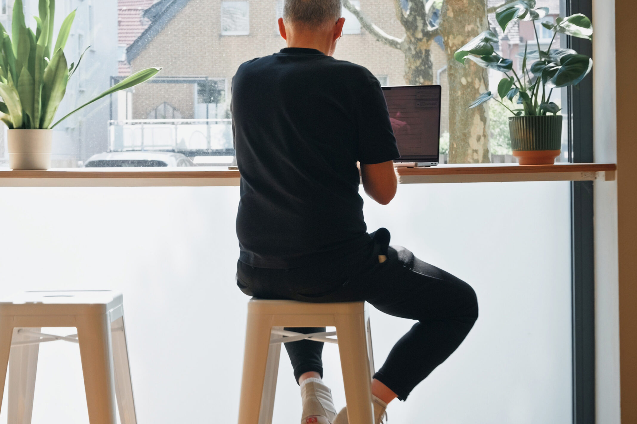 Mitarbeiter von seitenweise arbeitet am Laptop an der Fensterfront